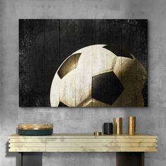 a soccer ball sitting on top of a wooden table next to a wall mounted painting