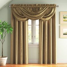 a living room filled with furniture and a window covered in drapes next to a potted plant