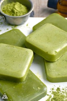 four pieces of green soap sitting on top of a white counter next to a bowl