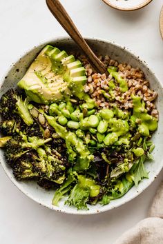 a white bowl filled with broccoli and other vegetables on top of a table