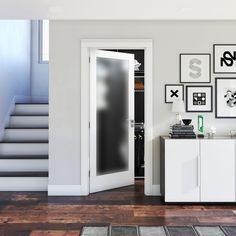 an open door in a white room with pictures on the wall and stairs leading up to it