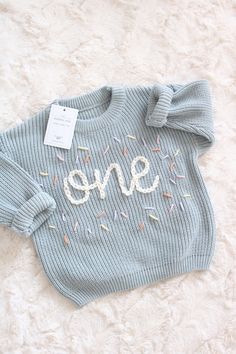 a blue sweater with sprinkles and the word one on it