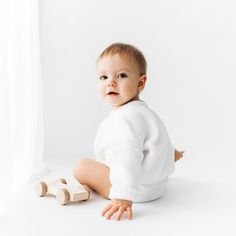 a baby sitting on the floor next to a wooden toy