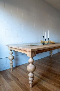 a wooden table sitting on top of a hard wood floor next to a white brick wall