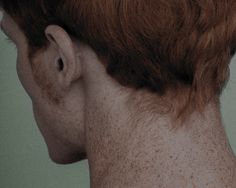 the back of a woman's head with freckles on her face and neck