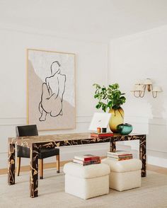 a living room with a table and two chairs in front of a painting on the wall