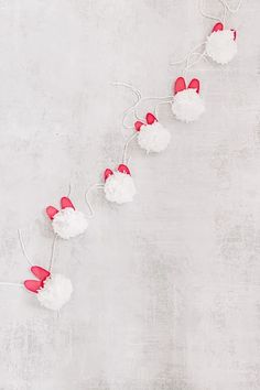 red and white pom - poms are strung up on a light gray background