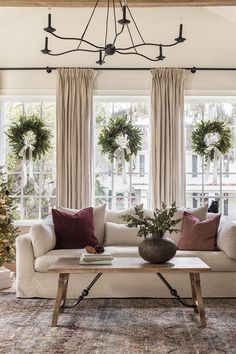 the living room is decorated for christmas with wreaths on the window sill and two couches