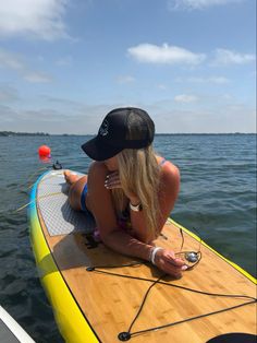 a woman sitting on top of a yellow surfboard in the middle of the ocean