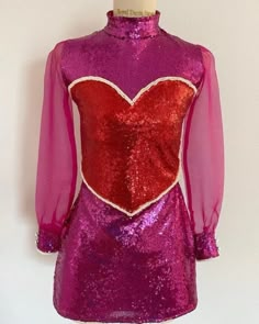 a pink and red dress with a heart on it's chest, sitting on a mannequin