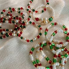 several bracelets with pearls and beads on a white tablecloth, some are green and red