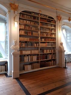 a large book shelf filled with lots of books on top of a hard wood floor