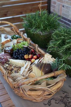 a wicker basket filled with assorted cheeses and fruit