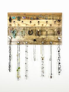 a wooden wall mounted with lots of necklaces and rings hanging from it's sides