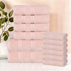 a stack of pink towels sitting on top of a white counter next to a plant