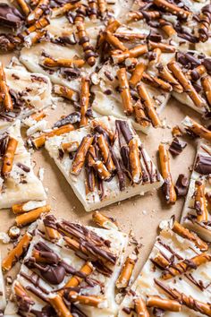 chocolate and pretzel crackers are arranged on a sheet of parchment paper with white icing