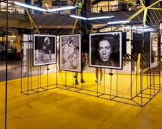 an art exhibit with three black and white pictures on display in the center, while two people are walking past them