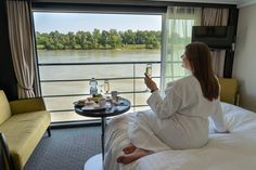 a woman sitting on a bed taking a selfie in front of a large window