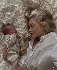 a woman laying on top of a bed holding a baby