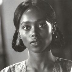 a black and white photo of a woman with large hoop earrings on her head looking at the camera