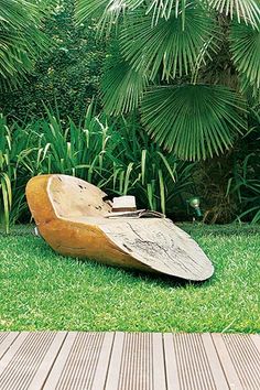 a wooden boat sitting on top of a green grass covered field next to palm trees