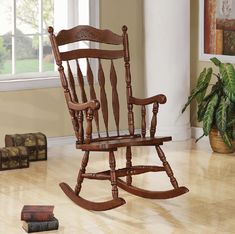 a wooden rocking chair sitting on top of a hard wood floor next to a window