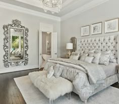 a bedroom with a bed, mirror and chandelier in the middle of it