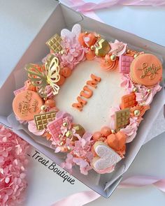 a birthday cake in a box with pink flowers and decorations on it's side