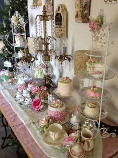 a table topped with lots of cakes and cupcakes next to a chandelier