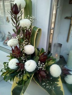 a vase filled with white flowers and greenery