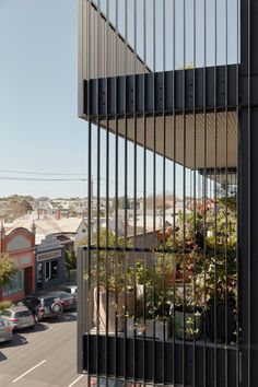 an apartment building is seen through the metal bars on the side of the street, with cars parked in front of it