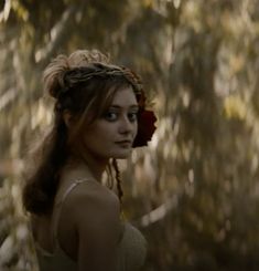 a woman with braids and a flower in her hair is looking at the camera