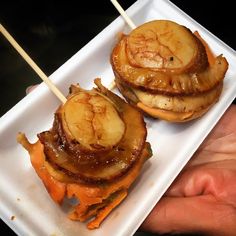 there are two food items on the plate with toothpicks in each one's hand