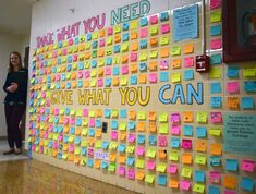 a woman standing next to a wall covered in post it notes