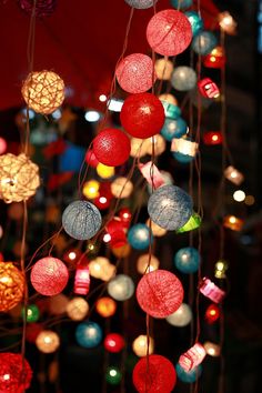 colorful lights are hanging from strings in the dark room with red and white umbrellas