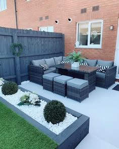 an outdoor living area with couches, tables and potted plants on the grass