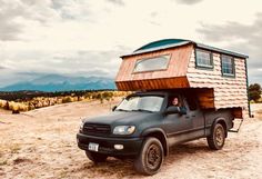 a woman sitting in the bed of a truck with a tiny house on it's roof