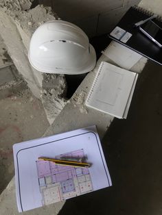 a white hard hat sitting on top of a piece of paper next to a yellow pencil