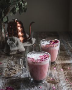 two mugs filled with pink liquid sitting on top of a table