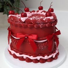 a red and white cake with cherries on top