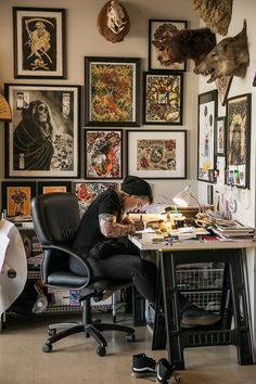 a man sitting at a desk in front of a bunch of pictures