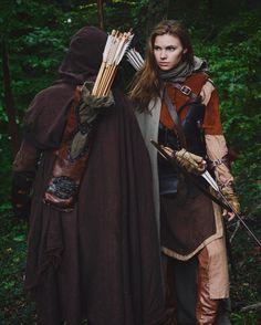 two people dressed up in costumes holding bows and arrows