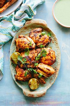 grilled chicken with herbs and lemons on a plate next to a glass of green juice