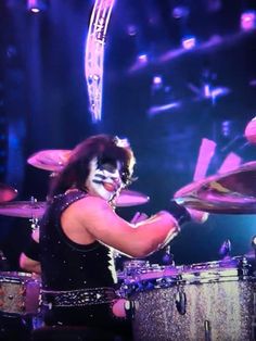 a woman with makeup playing drums on stage