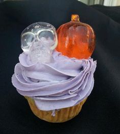 a cupcake with frosting and an orange pumpkin sitting on it's wrapper