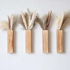 three wooden vases with dried plants in them