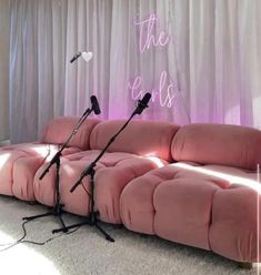 two microphones sitting on top of a pink couch in front of a white curtain