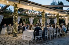 a group of people sitting around a table under a gazebo with lights on it