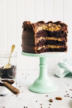 a chocolate cake sitting on top of a green cake stand next to a cup of coffee