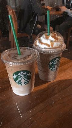 two starbucks drinks sitting on top of a wooden table